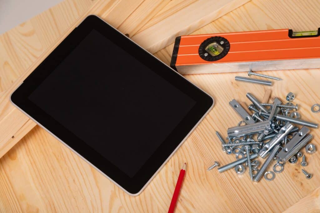 construction tool and a digital tablet lie on a light wooden table